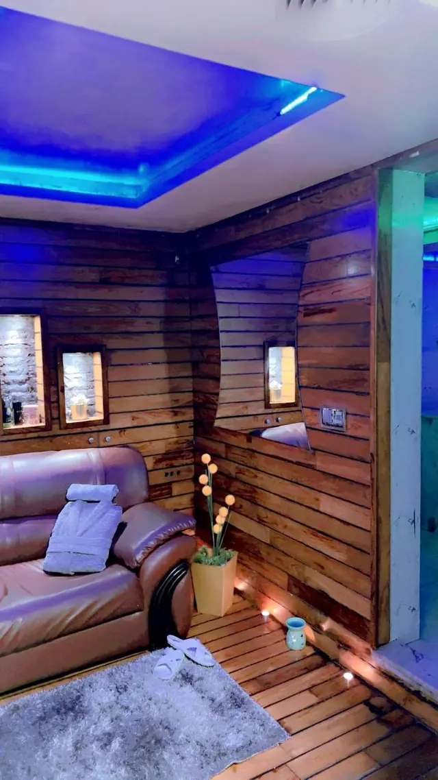Salon de détente en bois avec éclairage bleu et canapé au spa Glam House Casa, Casablanca
